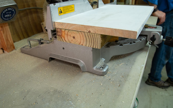 2x-6 board placed under workpiece to make a wider cut with miter saw