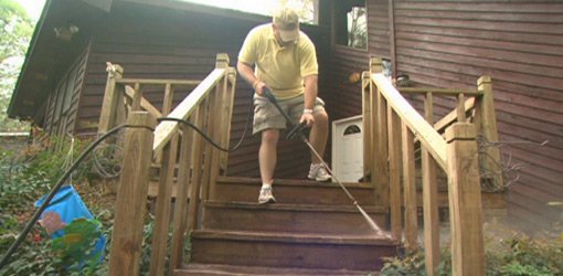 Cleaning deck steps with pressure washer.