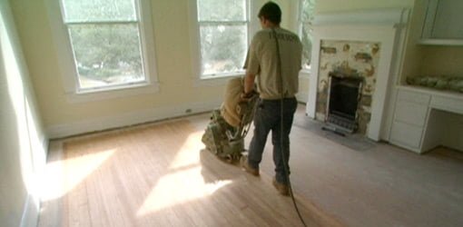 Sanding wood floor with floor sander.