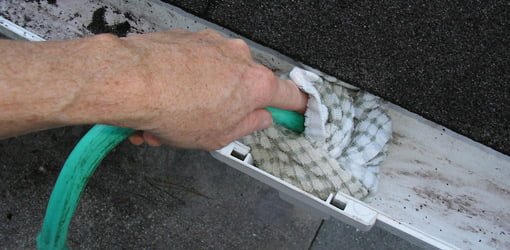 Using a garden hose to clear clogs in a downspout