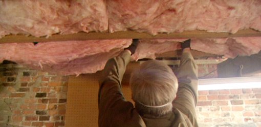 Danny Lipford installing fiberglass insulation under floor.