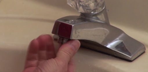 Unscrewing a faucet aerator for cleaning.