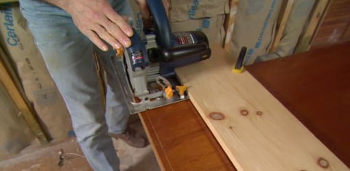 Using circular saw on clamped board guide to trim door bottom.
