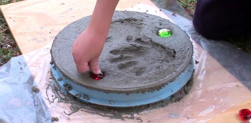 Pressing colored rocks into personalized stepping stone.