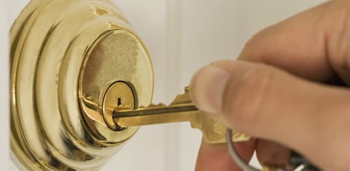 Key being inserted in deadbolt lock on door.