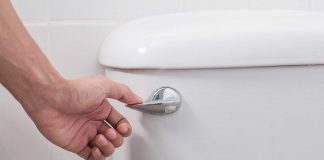 Closeup of woman's hand as she flushes a toilet that has a stuck handle