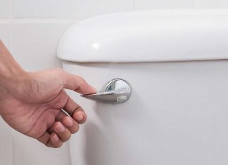 Closeup of woman's hand as she flushes a toilet that has a stuck handle