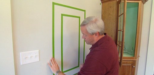 Danny Lipford applying painter's tape to wall