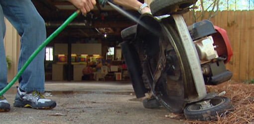 Cleaning the underside of a lawn mower with a garden hose