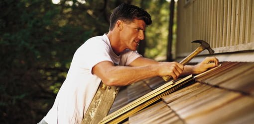 Roofer roofing house with wood shingles.
