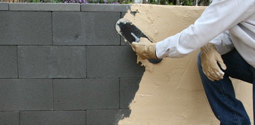 Applying surface-bonding cement to a dry stacked concrete block wall