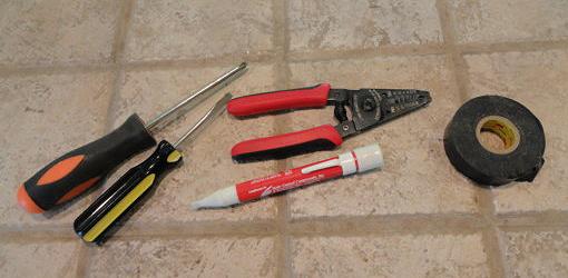 Screwdrivers, wire strippers, voltage tester, and electrical tape