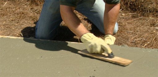 Using a wood float to smooth surface of concrete slab