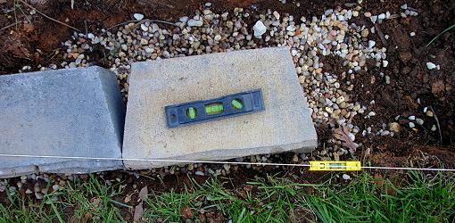 Leveling blocks for a retaining wall on a gravel base
