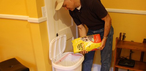 Joe Truini pouring kitty litter into garbage can bag