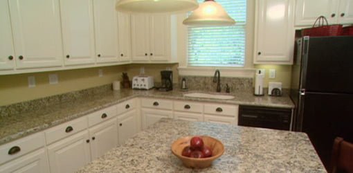 Remodeled kitchen with white painted cabinets and granite countertops.