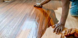 Man stains heart pine wood floors by hand