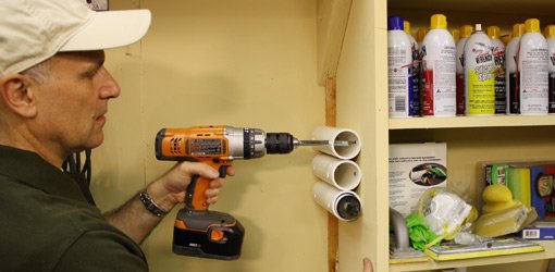 Screwing PVC pipe caulking tube holder to side of shelves.