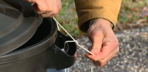 Tying trash can lid to can with string