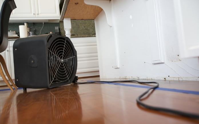 An industrial fan dries out water damaged kitchen cabinets