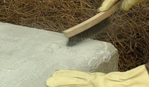 Using wire brush to remove loose concrete material