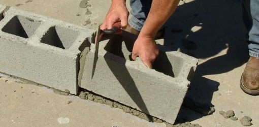 Laying concrete blocks for a wall.