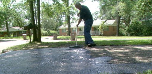 Danny Lipford applying asphalt sealer to driveway.