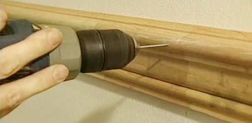 Drilling a hole in chair rail using a drill bit made from a nail.