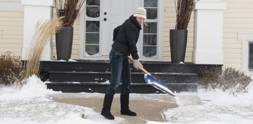 Shoveling snow on sidewalk in front of house.