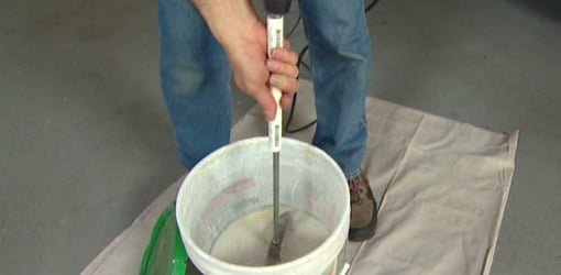 Using homemade PVC pipe paddle mixer handle to mix joint compound in bucket.