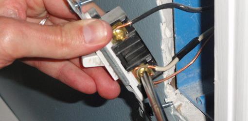 Attaching wires to a wall switch.