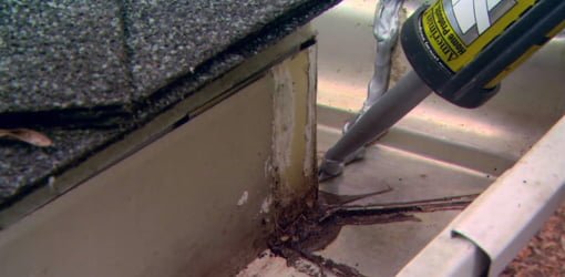 Using gutter seal caulk to repair a leaking joint in a gutter.