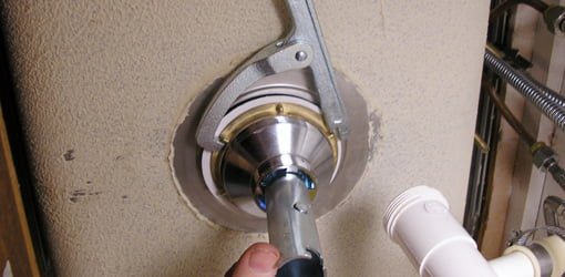 Usando la llave de colador del fregadero para apretar la tuerca de seguridad en el colador del fregadero.