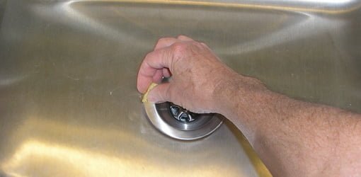 Het verwijderen van overtollig loodgietersplamuur rond het nieuwe gootsteenzeefje.'s putty around new kitchen sink strainer.