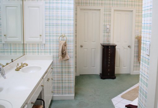 Bathroom before remodel with plaid wallpaper and carpet on the floor.