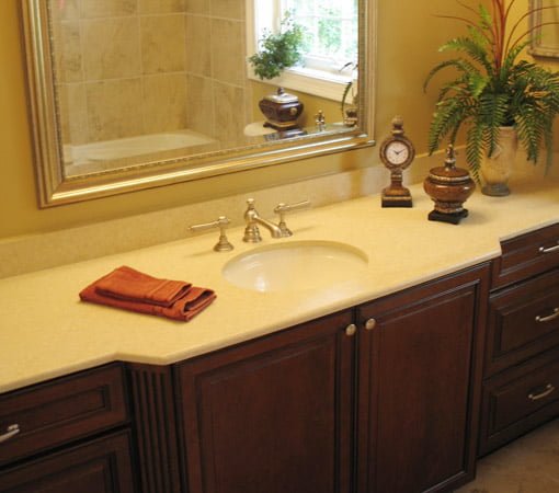 Remodeled bathroom with stained wood cabinet and solid surface countertop.