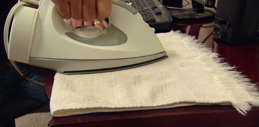 Using a warm clothes iron and cloth to remove water marks from furniture.