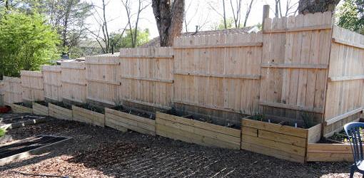 Raised bed planters used to fill the gaps at the bottom of the fence above.