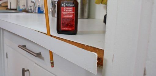 Using a pencil to hold plastic laminate edging away from countertop while contact cement dries.