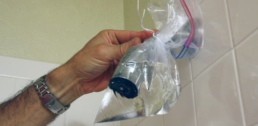 Using vinegar in a plastic bag to clean a clogged showerhead.