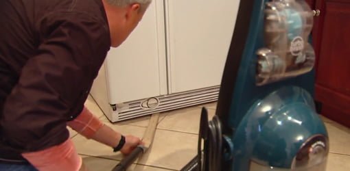 Danny Lipford cleaning under a refrigerator.