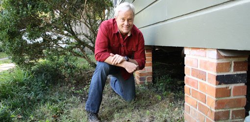Danny Lipford inspecting for termites under a house.