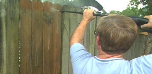Using a pressure washer to clean a wood fence.