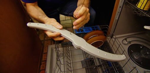 Using wire from a coat hanger to clean the holes on dishwasher spray arms.