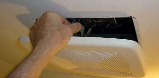 Pressing the spring clips together to remove vent fan cover.