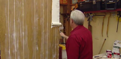 Danny Lipford priming wall paneling with a paint roller.