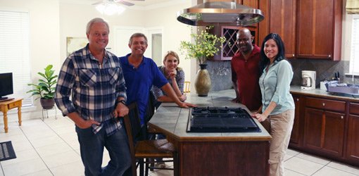 Today's Homeowner crew and contest winners standing around kitchen island with new Broan range hood.
