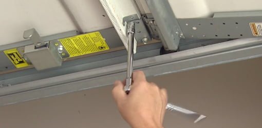 Using socket wrench to tighten a loose bolt on garage door.