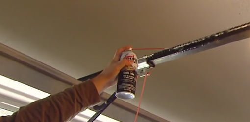 Using spray lubricant to lubricate the track on a garage door.