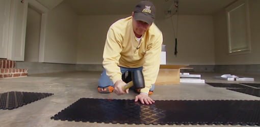 Using a rubber mallet to Install interlocking rubber tiles on a garage floor.